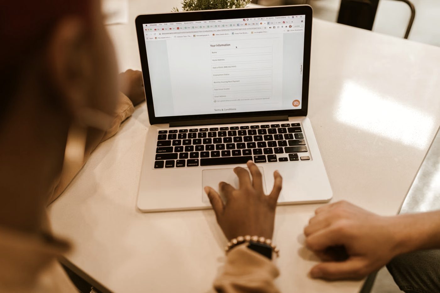 Two people filling in a form together on a laptop